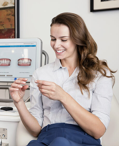 Smiling women holding and looking at Invisalign